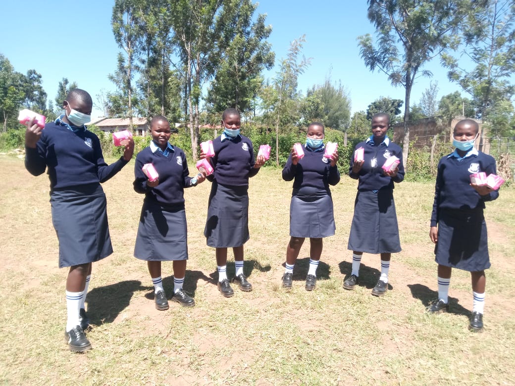 Girls carrying packets of sanitary pads